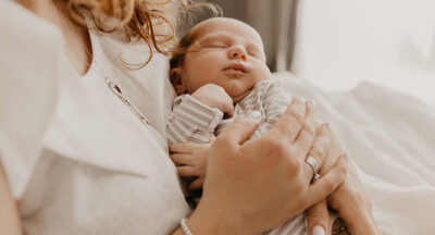 Woman in white long sleeve shirt carrying baby